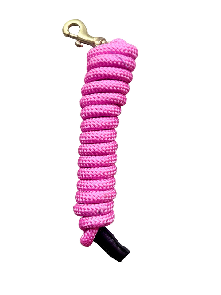 A pink coiled rope keychain or leash-style accessory with a gold metal clasp at the top and a black loop at the bottom, photographed on a gray concrete surface.